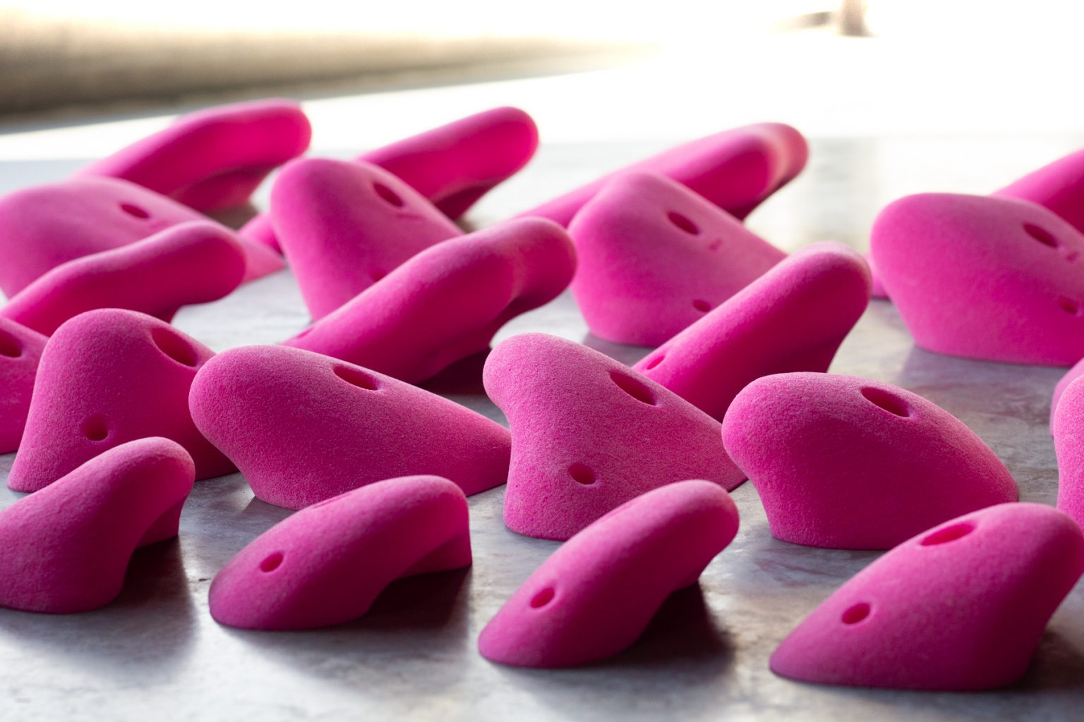 Pink climbing holds laid out on a table