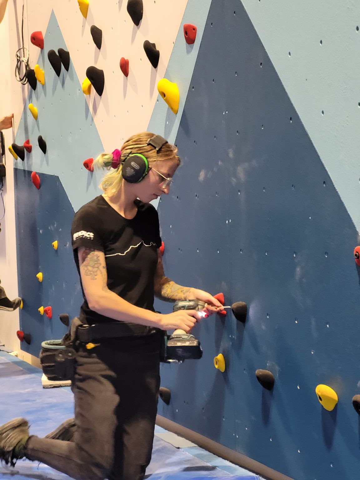 The Art of Route Setting 5 Route setter fitting holds on a climbing wall