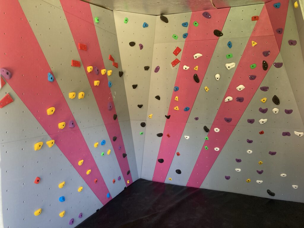 Custom home bouldering wall with grey panels and pink stripes, built by Project Climbing